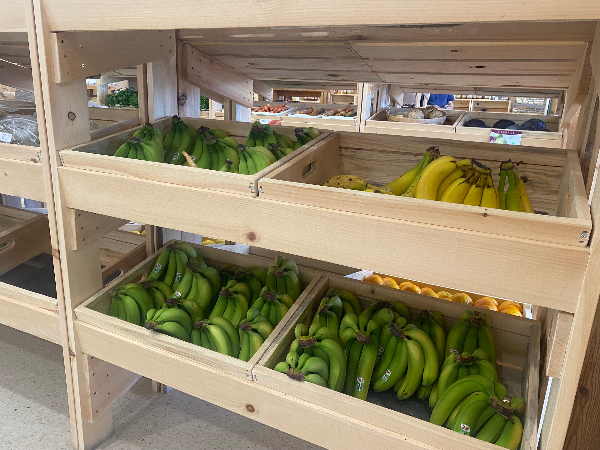 Wooden crates of fresh bananas and oranges in the produce section
