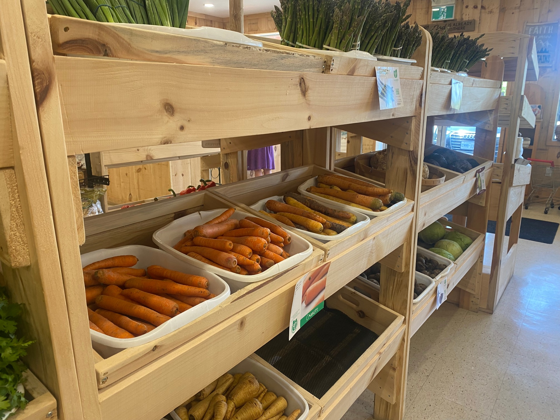 Fresh carrots and seasonal produce on wooden crate shelves inside the market